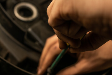 The hands of a mechanic adjusting a part with a screwdriver.