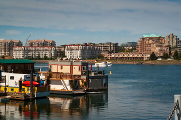 Fototapeta na wymiar Boat houses at Fisherman wharf with apartments buildings in background in Victoria, British Columbia, Canada