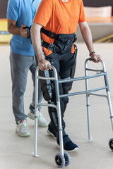 Boy with Mobility Problems in Lower Limbs in Upright Posture Walking Thanks to a Mechanical...