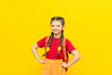 A schoolgirl with a satchel is getting ready to go to school. Children's education. Preparatory courses for schoolchildren. Additional classes for successful exams. Yellow isolated background.