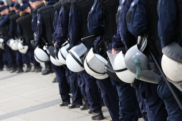Policjanci prewencji w mundurach i tarczami idą na akcję w szeregu. 
