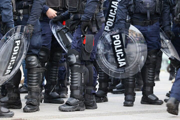 Policjanci prewencji w mundurach i tarczami idą na akcję w szeregu.  - obrazy, fototapety, plakaty