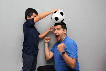 Hispanic dad and son share their love for soccer, they take a ball with their hands excited to...