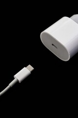 White european plug fast charger block and type-c cable on the left isolated on black background....