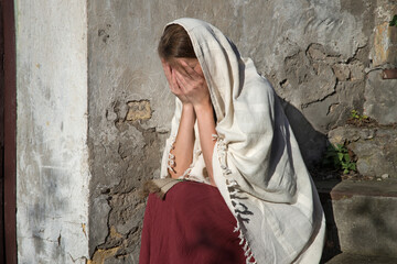 Naklejka premium Sad woman in ancient clothes sitting on the steps
