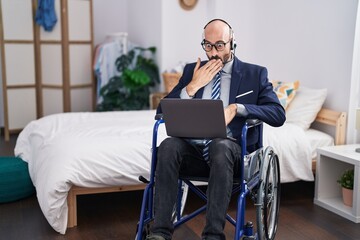 Hispanic man with beard sitting on wheelchair doing business video call covering mouth with hand,...