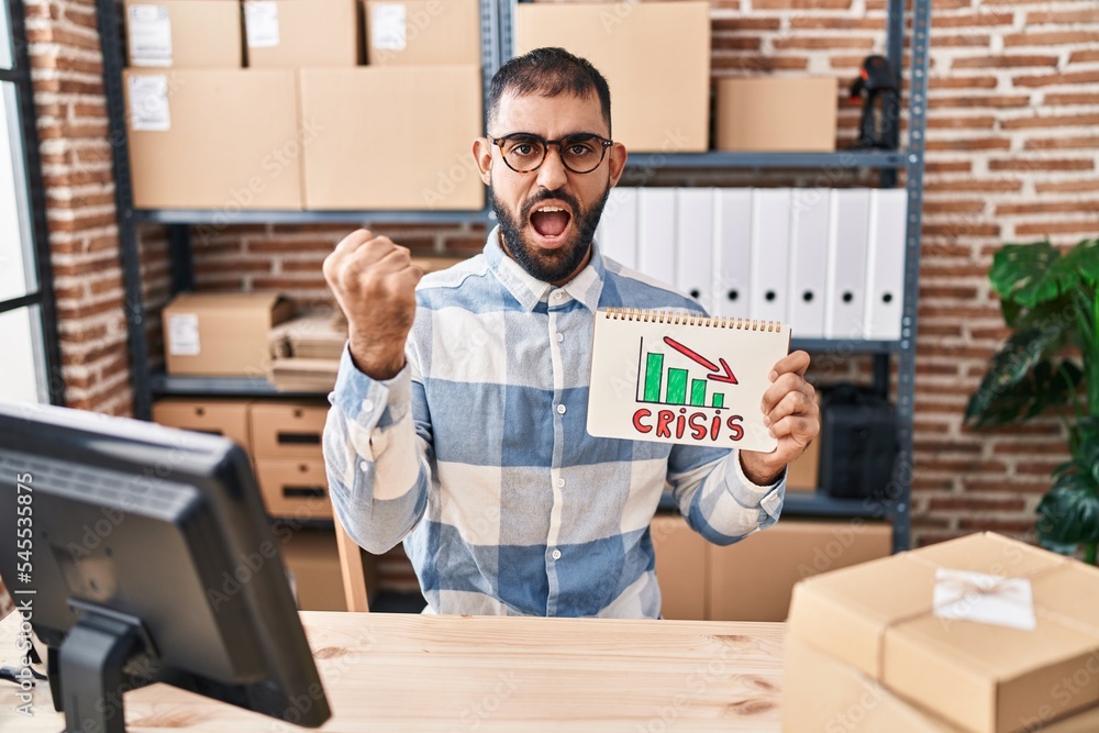 Sticker Middle east man with beard working at small business ecommerce holding crisis banner annoyed and frustrated shouting with anger, yelling crazy with anger and hand raised