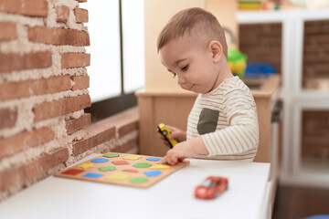 Adorable toddler playing with maths game on table at home