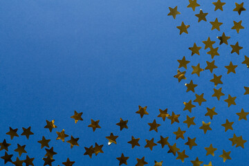 Golden confetti stars on color background, top view