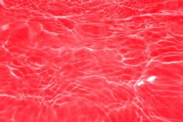 Defocus blurred transparent red colored clear calm water surface texture with splashes and bubbles. Trendy abstract nature background. Water waves in sunlight with copy space. Red watercolor shining