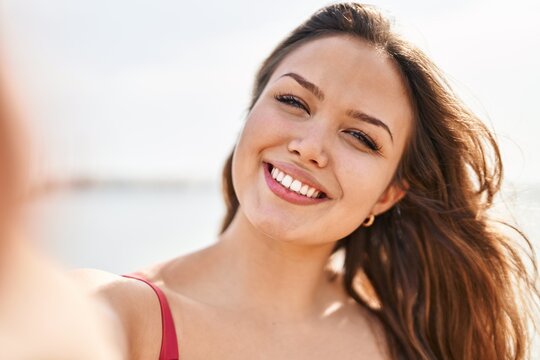 Young beautiful hispanic woman tourist smiling confident make selfie by camera at beach