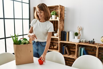 Young caucasian woman holding food of groceries paper bag at home