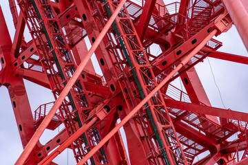 Close-up of fragment of red cable-stayed bridge pylon in place where metal cables are fastened. Close-up shows connection of steel powerful straight crossbar, bridge connection, metal architecture.