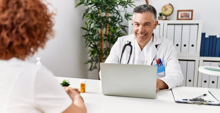 Middle age man and woman wearing doctor uniform having medical consultation at clinic