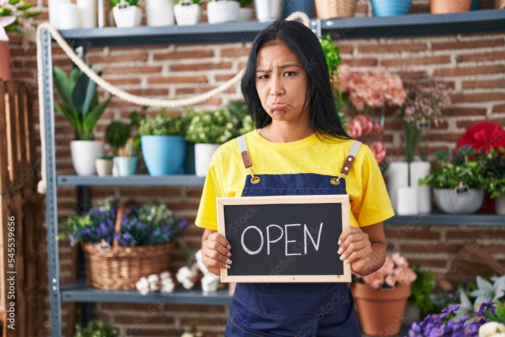 Sticker Hispanic woman working at florist holding open sign depressed and worry for distress, crying angry and afraid. sad expression.