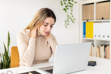 Young business woman suffering neck pain working on laptop at home - Health problems at work