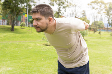 man stretching his arms behind him to exercise in the park