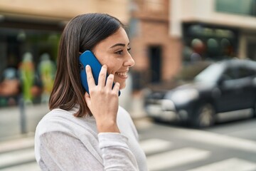 Young hispanic woman smiling confident talking on the smartphone at street