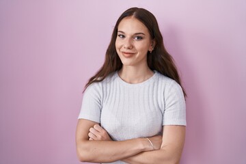 Fototapeta premium Young hispanic girl standing over pink background happy face smiling with crossed arms looking at the camera. positive person.