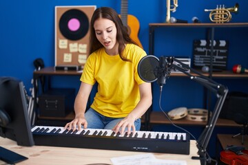 Fototapeta na wymiar Young woman musician singing song playing piano keyboard at music studio