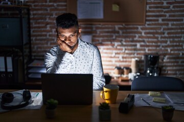 Young hispanic man working at the office at night thinking looking tired and bored with depression...