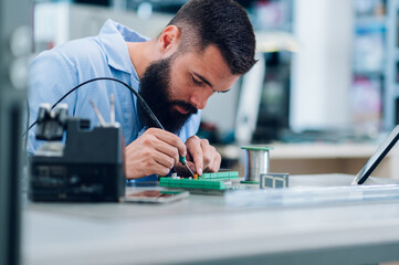 Electronics engineer working in a workshop with tin soldering parts