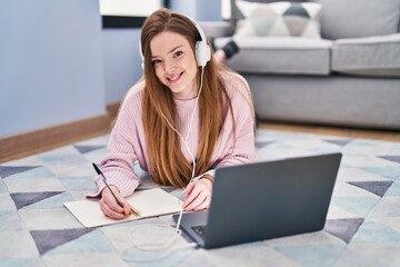 Young caucasian woman listening to music and studying at home