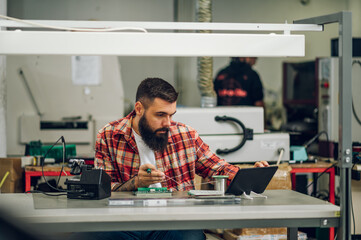 Fototapeta premium Electronics engineer working in a workshop with tin soldering parts