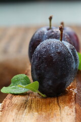  Plums on a wooden table with water droplets.