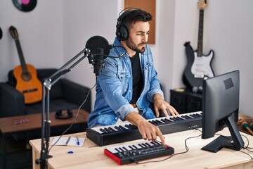 Young hispanic man composer composing song at music studio