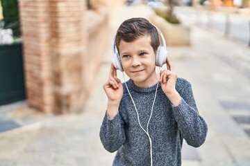 Blond child smiling confident listening to music at street