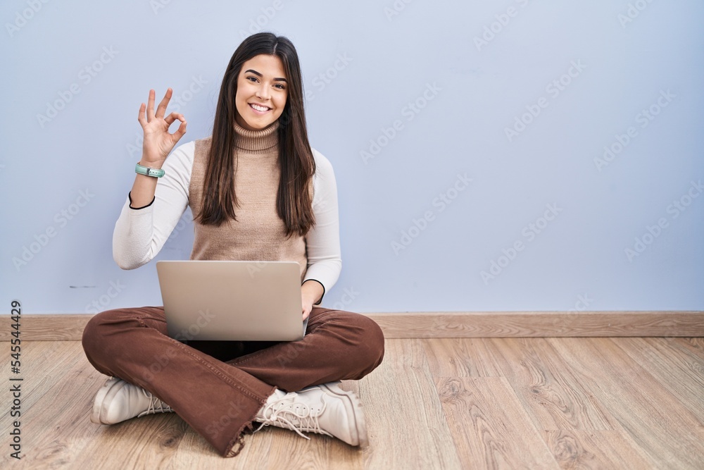 Sticker young brunette woman working using computer laptop sitting on the floor smiling positive doing ok si