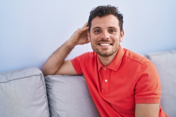 Young hispanic man smiling confident sitting on sofa at home