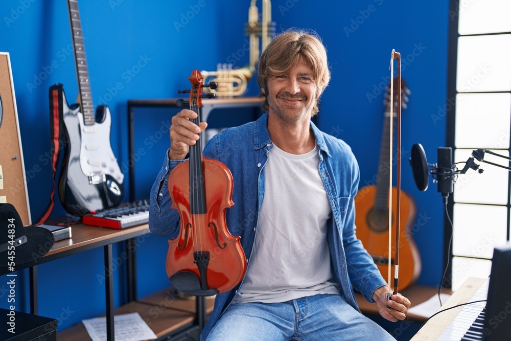 Sticker Young man musician holding violin at music studio