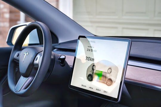 Toronto, Ontario, Canada - Nov 10, 2022 :  Tesla control panel screen showing battery charging progress. Tesla interior steering wheel with logo.