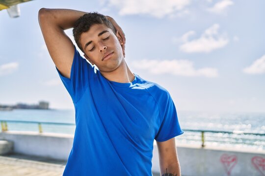 Young hispanic man stretching neck muscles outdoors