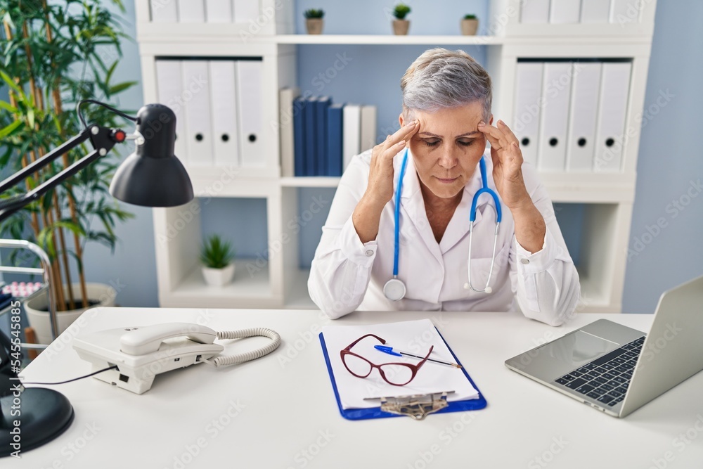 Canvas Prints Middle age woman wearing doctor uniform stressed working at clinic