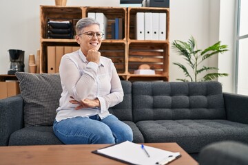 Middle age woman psychologist sitting on sofa at pyschology center