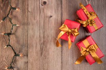 Three gifts and christmas lights on wooden background