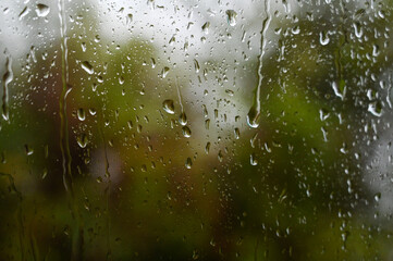Droplet on the window glass. Raindrop on car glass and green forest in background. Rainy day at spring. Water drops. Background.