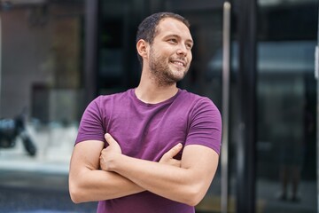 Young man smiling confident standing with arms crossed gesture at street