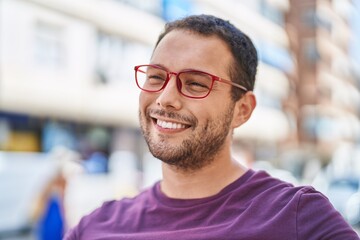 Fototapeta premium Young man smiling confident wearing glasses at street