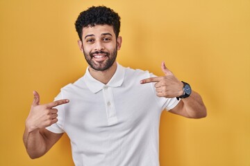 Arab man standing over yellow background looking confident with smile on face, pointing oneself...
