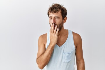 Young handsome man standing over isolated background bored yawning tired covering mouth with hand. restless and sleepiness.