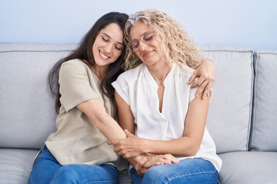 Two women mother and daughter hugging each other at home