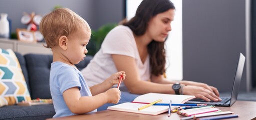 Mother and son drawing on notebook using laptop at home