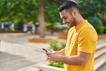 Fototapeta premium Young hispanic man smiling confident using smartphone at park