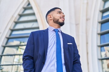Young latin man business worker smiling confident looking to the sky at street