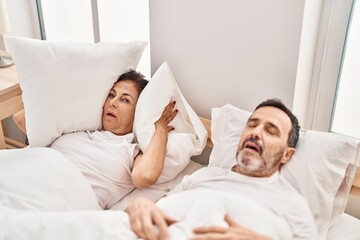 Middle age man and woman couple unhappy for snoring at bedroom