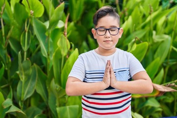 Adorable hispanic boy doing yoga exercise at park